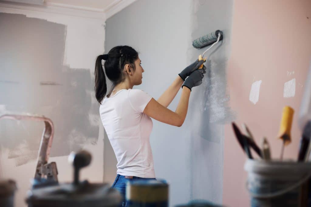 Young woman with hearing aid painting walls