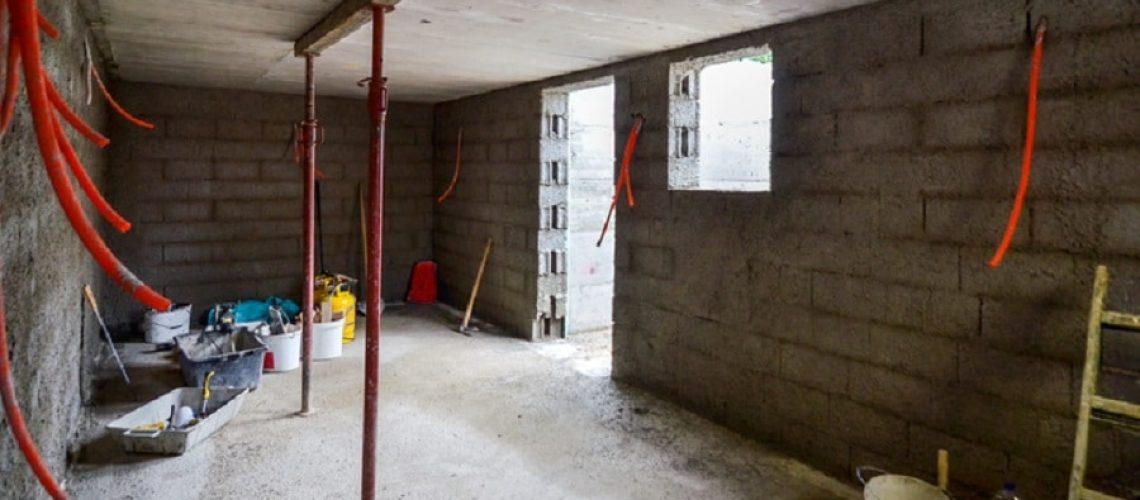 Plastering, rebuilding, waterproofing basement or a cellar and work tools. Construction of residential house cellar or basement with electric installations and freshly plastered walls.