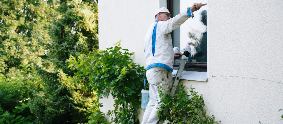 House painter paints the window frame from the outside